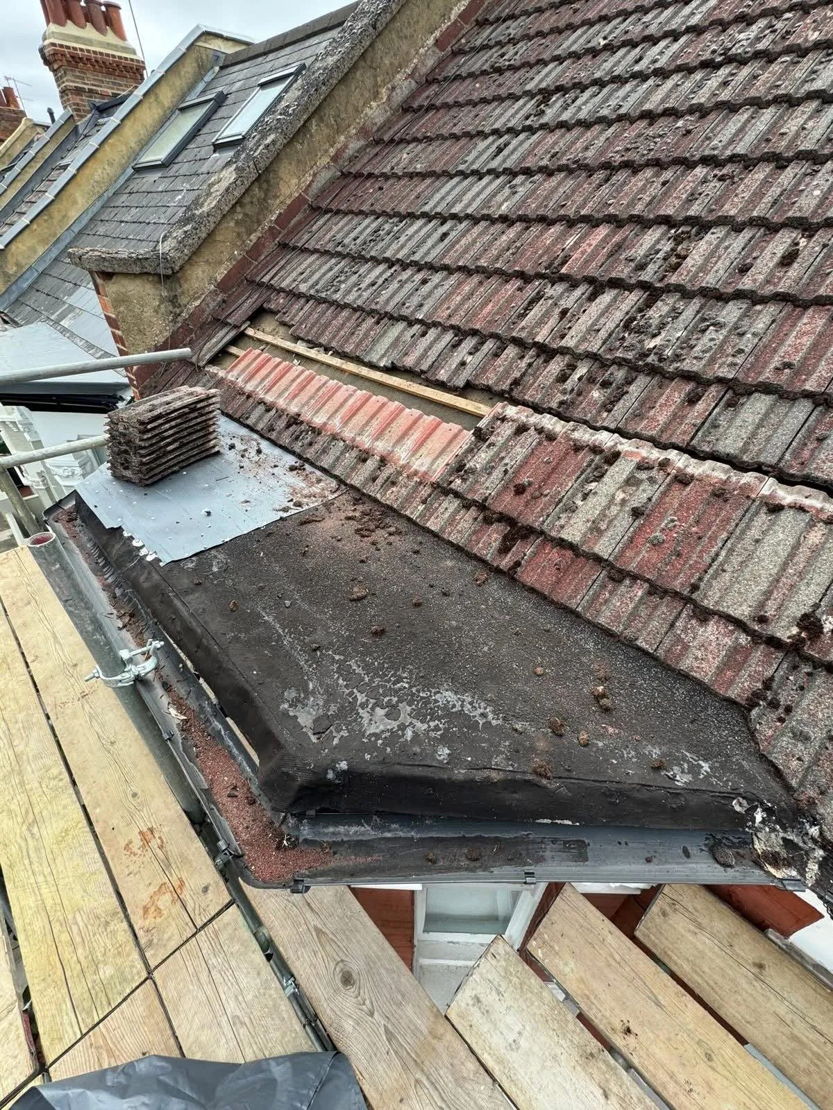 Worn tiled roof above a flat roof section