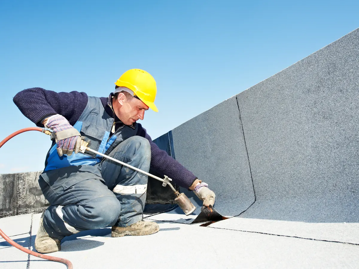 Roofer sealing a membrane on a large commercial flat roof