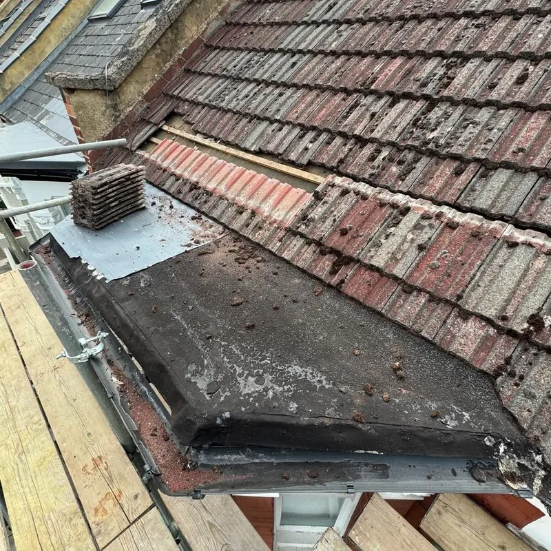 Worn tiled roof above a flat roof section, ready for repair